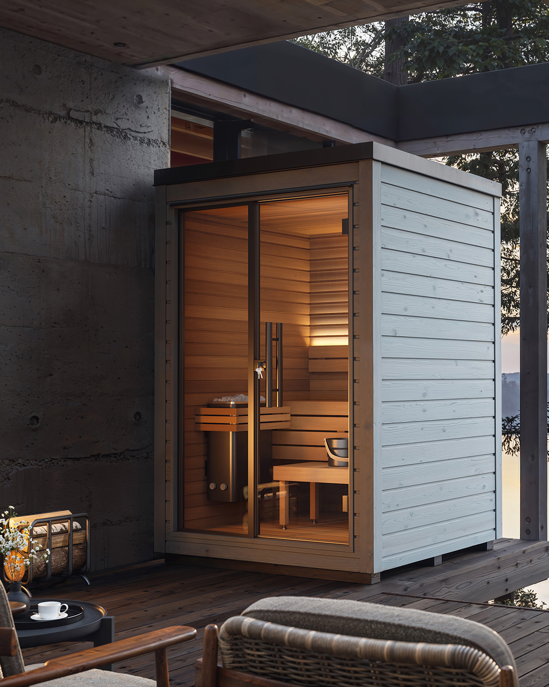 Auroom Mira compact outdoor sauna in a light grey exterior finish, installed on a modern terrace with warm interior lighting and Scandinavian design details.