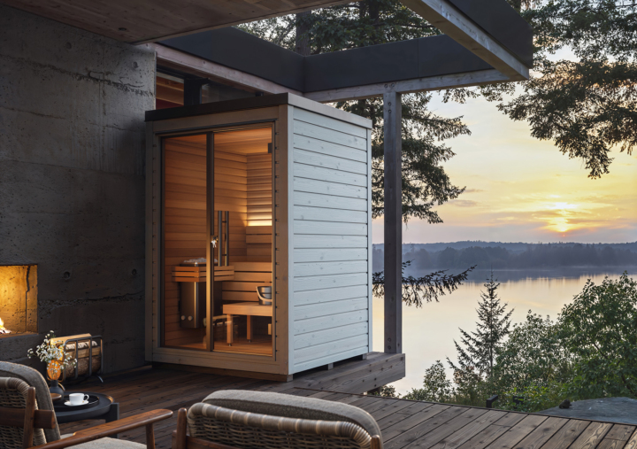 Auroom Mira compact outdoor sauna in a light grey exterior finish, installed on a modern terrace with warm interior lighting and Scandinavian design details.