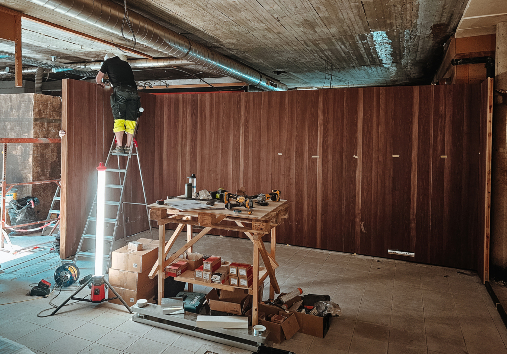 On-site installation of a custom modular indoor sauna with dark wood wall panels and fast assembly process